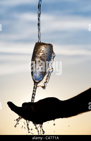 L'eau est versée dans une flûte à champagne. Silhouette Banque D'Images