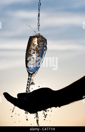 L'eau est versée dans une flûte à champagne. Silhouette Banque D'Images