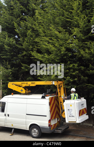 BT engineer remplacement arbre endommagé le câble téléphonique à l'aide d'une plate-forme de levage mobile dans une rue de banlieue anglaise. Banque D'Images