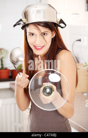 Chevalier cuisine - belle jeune femme de race blanche dans la cuisine avec un pot sur la tête (casque) et que hohl (comme épée) Banque D'Images