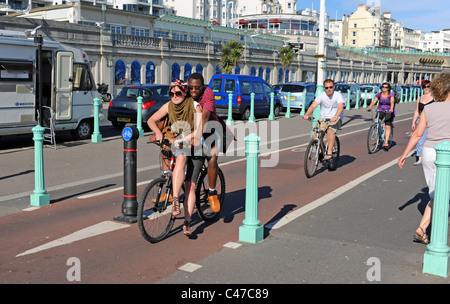 Couple Profitez d'une balade en vélo le long de front de mer de Brighton avec femme en équilibre sur le vélo cross bar UK Banque D'Images