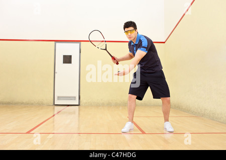 Joueuse de squash au service d'une balle dans un court de squash Banque D'Images