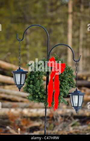 Un éclairage d'entrée à Seeley Lake Montana est décorée avec une couronne de Noël et arc rouge. Banque D'Images