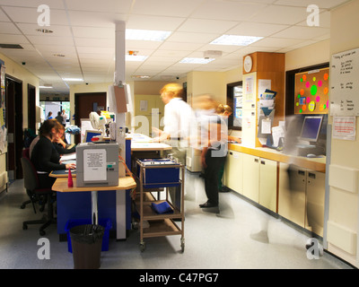 Occupé à UK NHS Hospital Ward, avec les médecins et les infirmières se précipiter sur, brouillées, montrant mouvement et d'action Banque D'Images