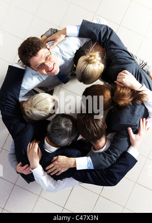 Voir ci-dessus de plusieurs partenaires enlacés tout en faisant un cercle avec l'un d'entre eux looking at camera Banque D'Images