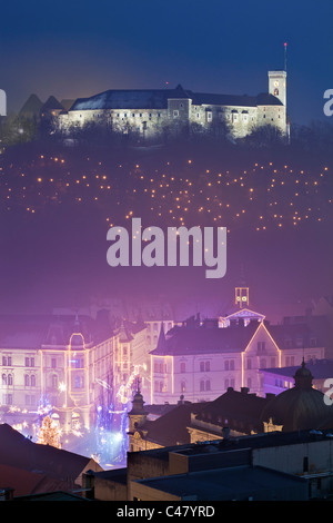 Le Château de Ljubljana et le centre-ville décoré de lumières pour les fêtes, la création d'une lueur colorée dans le brouillard du soir. Banque D'Images