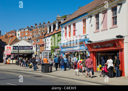 Les touristes se promenant à proximité des magasins sur le front de mer à Spring Foreshore Road Scarborough North Yorkshire Angleterre Royaume-Uni Grande-Bretagne Banque D'Images