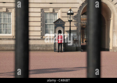 Une vue à travers les grilles à l'extérieur de Buckingham Palace, London, UK. d'un soldat de l'imprimeur de la garde. Banque D'Images