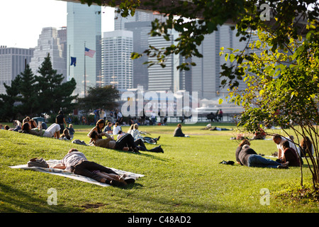 Les gens allongés sur l'herbe sous le pont de Brooklyn, New York City, USA Banque D'Images