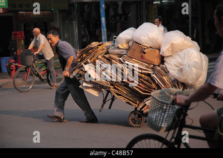 L'homme tire le panier plein de produits recyclables, Guangzhou, Chine Banque D'Images