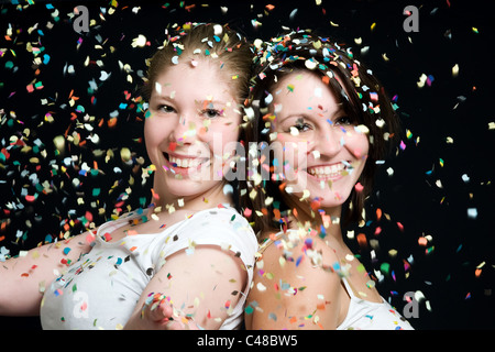 Deux jeunes femmes jetant confetti Banque D'Images