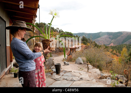 Une femme et sa fille sourire à l'autre comme une plante d'eau ils de l'eau de pluie à l'extérieur de leur maison du Colorado à l'automne. Banque D'Images