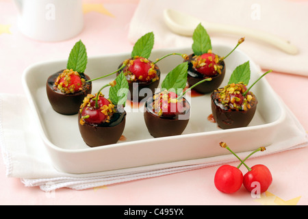 Peu de chocolat tasses avec les cerises. Recette disponible.. Banque D'Images