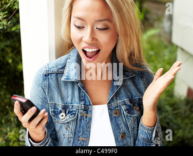 Fille de la réception du message excité sur son téléphone Banque D'Images