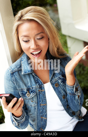 Fille de la réception du message excité sur son téléphone Banque D'Images