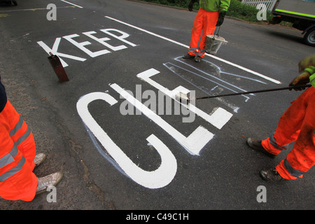 Marquage routier, piste de route, garder à l'écart, Santé et sécurité, peinture de route, Hommes au travail, peinture pour chariot, marqueur de ligne, suivant la ligne de trottoir, repère jaune. Banque D'Images