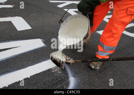 Marquage routier, piste de route, garder à l'écart, Santé et sécurité, peinture de route, Hommes au travail, peinture pour chariot, marqueur de ligne, suivant la ligne de trottoir, repère jaune. Banque D'Images