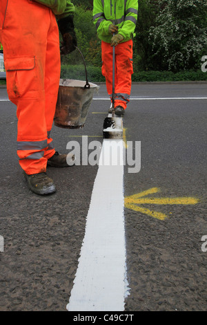 Marquage routier, piste de route, garder à l'écart, Santé et sécurité, peinture de route, Hommes au travail, peinture pour chariot, marqueur de ligne, suivant la ligne de trottoir, repère jaune. Banque D'Images