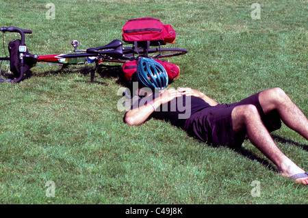 Cycliste allongé sur le dos dans l'herbe, l'homme endormi sur le sol et se reposer à côté de location Banque D'Images