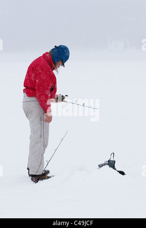 Une femme à la pêche sur glace sur un lac gelé Banque D'Images