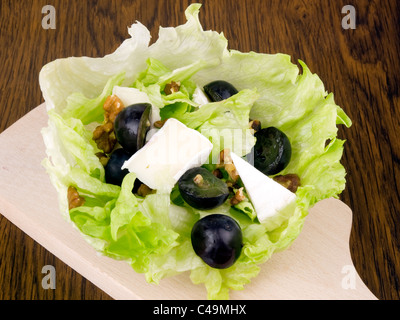 Salade savoureuse avec le camembert, raisins noirs et les noix dans la feuille de laitue iceberg sur planche à découper Banque D'Images