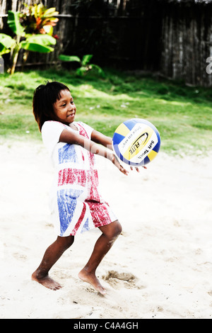 Portrait d'une jeune fille Kuna jouer au volley-ball dans son arrière-cour sur l'île dans l'Nalunega archipel des San Blas, Panama Banque D'Images