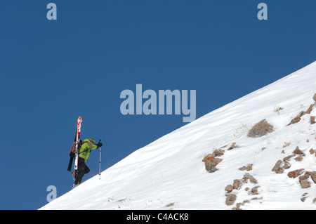 Trois alpinistes de ski skis transportant sur une ligne de crête couverte de neige contre un ciel bleu profond à Dizin Iran Banque D'Images