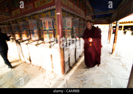 Un moine bouddhiste tibétain de tourner les roues de prière pendant qu'il marche autour de la Kora monastère Labrang. ( Effet spécial de flou ) Banque D'Images