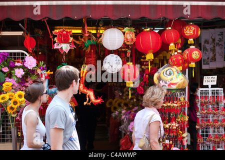 Singapour, Singapour, Chinatown. Les touristes passent devant les décorations du Nouvel An chinois à vendre sur Temple Street. Banque D'Images