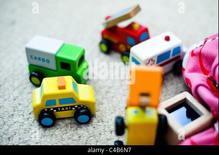 Un petit groupe d'enfants jouet en bois peint de véhicules sur un tapis neutre. Banque D'Images