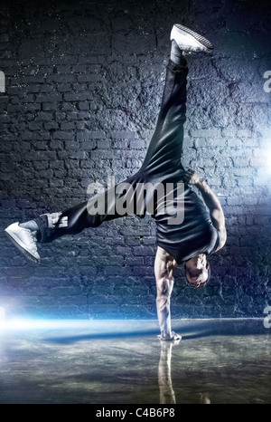 Jeune homme fort break dance. Sur le mur sombre arrière-plan. Banque D'Images