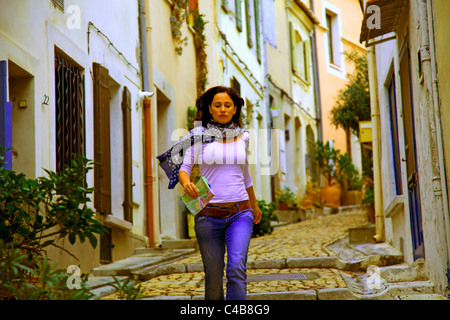 Arles, Bouches du Rhône, France ; une jeune femme marchant dans les rues pavées de la ville. M. Banque D'Images