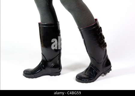 Au-dessous du genou tourné d'une paire de jambes de femmes en noir marche wellies, ou bottes prises sur un fond blanc. Banque D'Images