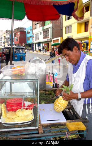 Vendeur de rue taille un ananas à Lima, Pérou. Banque D'Images