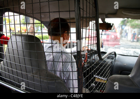 Chauffeur de taxi entouré d'une cage pour la sécurité à Lima, Pérou. Banque D'Images