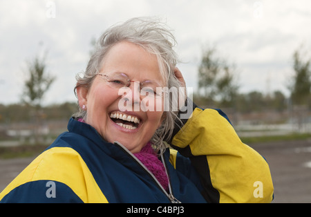 Femme hauts rire joyeusement, en plein air dans un jour nuageux venteux Banque D'Images