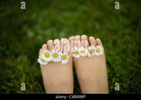 Petite fille de cinq ans avec daisies entre ses orteils Banque D'Images