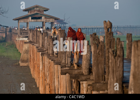 À l'aube du lac Taungthaman avec deux moines marchant sur le pont Ubein. Banque D'Images