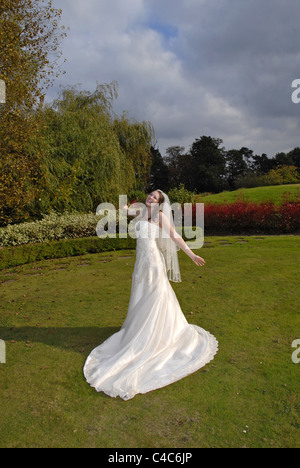 Image Portrait d'une belle épouse dans sa robe de mariée et voile ronde virevoltante et se sentir libre dans des jardins colorés Banque D'Images