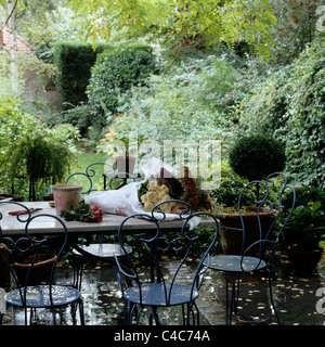 Meubles en fer forgé en plein air sur la terrasse de jardin humide Banque D'Images