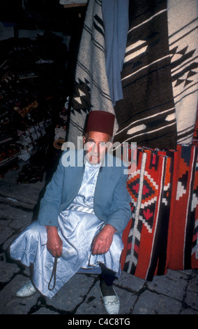 Homme assis à l'extérieur d'un magasin de tapis dans le sud d'Alep à, Syrie 1984 Banque D'Images