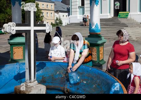 Dame remplissant sa bouteille d'eau bénite de la fontaine à l'intérieur de la Trinité, Monastère de Saint Serge à Serguiev Posad, Russie Banque D'Images