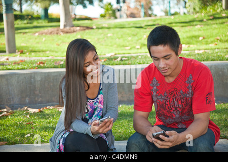 Deux multi raciale ethnique Californie diversifiés sur les adolescents des messages à l'aide d'iPhone Blackfoot American Indian, hispanique teens téléphone mobile device. M. Banque D'Images