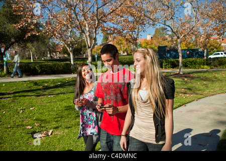 Divers groupes ethniques multiples de Pieds-noirs Américains de race blanche, à l'aide d'adolescents hispaniques téléphone portable iPhone 3 3 marche à pied. M. © Myrleen Pearson Banque D'Images