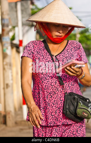 Femme portant chapeau conique vente de billets de loterie Banque D'Images