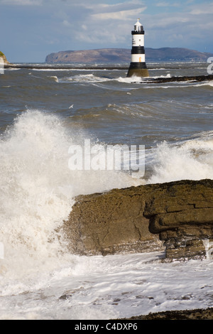 Penmon Point, l'île d'Anglesey, dans le Nord du Pays de Galles, Royaume-Uni. L'état de la mer par temps venteux en grandes vagues sur phare Penmon côte rocheuse Banque D'Images