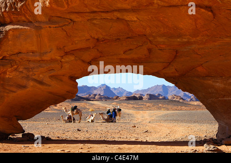 Caravane de chameaux des camps de nomades Touareg à un rocher en forme d'arche par l'érosion éolienne, l'Acacus montagnes, désert du Sahara, la Libye Banque D'Images