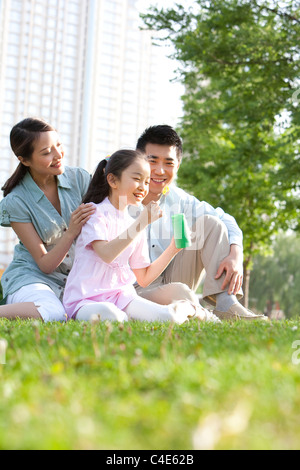 Famille faisant des bulles dans le parc Banque D'Images