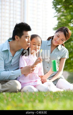 Famille faisant des bulles dans le parc Banque D'Images