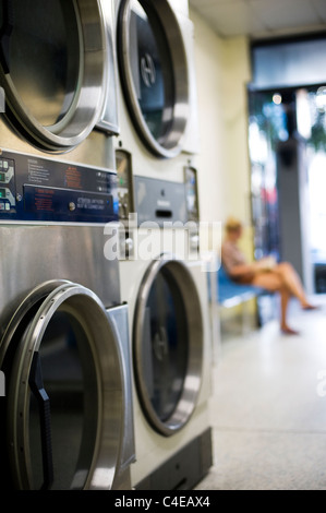 Jeune fille en attente de lavage dans une laverie automatique Banque D'Images